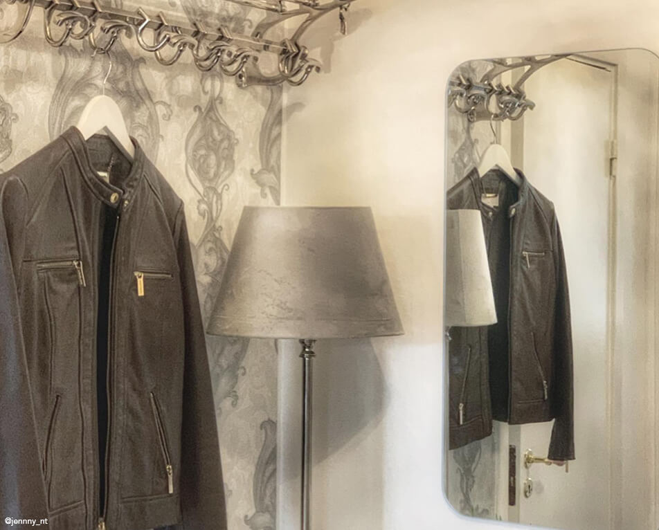 Wystrój przedpokoju - wieszak na ubrania, metalowe haczyki, prostokątne lustro i szara lampa