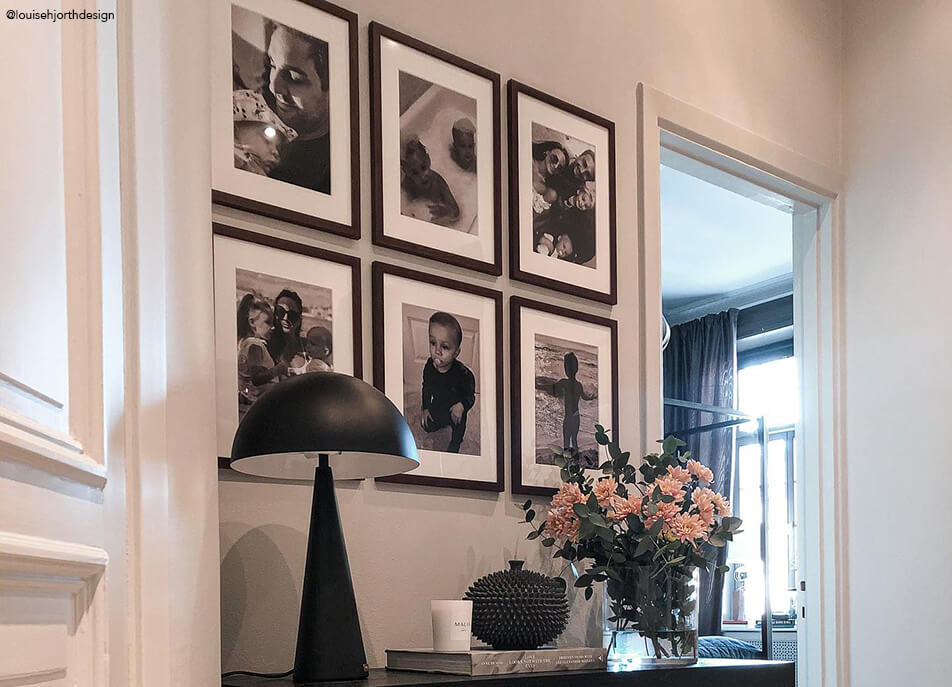 Galeria zdjęć w holu, czarno-białe zdjęcia w ciemnych ramach